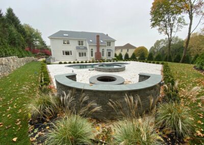 A serene backyard featuring a stone fountain and a grand house surrounded by nature's beauty.